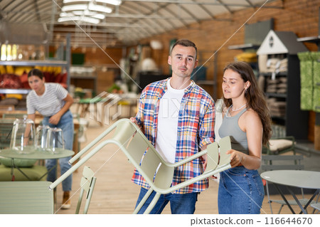 Spouses buyer choose chair in garden furniture store showroom 116644670