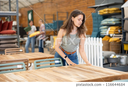 Positive girl choosing patio table at garden store 116644684