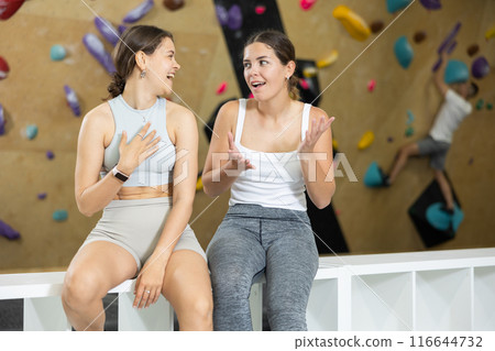 Girls chatting casually during break between climbs in bouldering gym 116644732