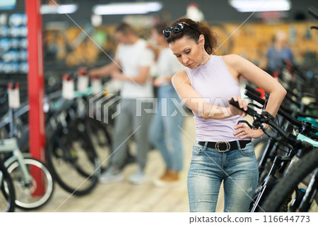 Active woman in bicycle shop chooses sports bike from range 116644773