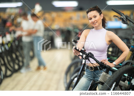 Active woman in bicycle shop chooses sports bike from range Active woman in bicycle shop chooses sports bike from range 116644807
