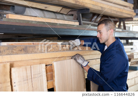 Young man takes oak plank from stack 116644826