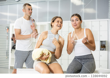 Young man intervenes in conversation between two girls in dressing room. 116644892