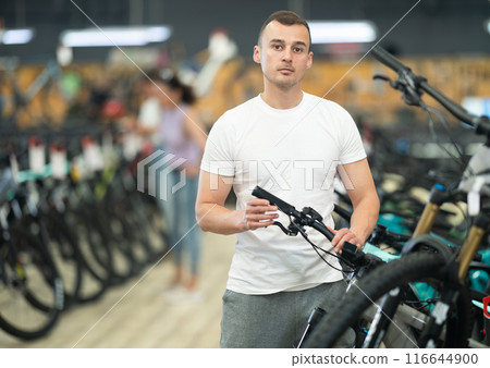 Interested man examining bike handlebar system in store Interested man examining bike handlebar system in store 116644900