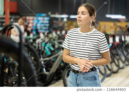 Young woman standing in bicycle shop and choosing new sport bike 116644903