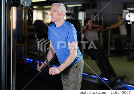 Mature man in sportswear training on rope loop simulator in gym 116645067