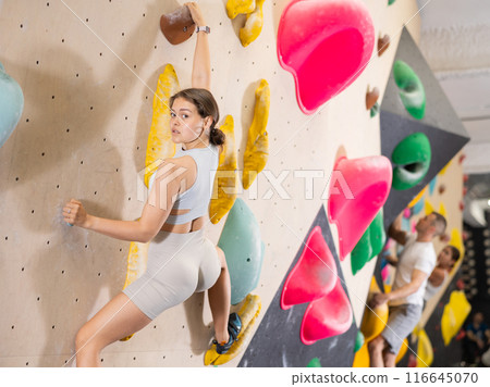 Young girl moving on bouldering wall at indoor climbing gym 116645070