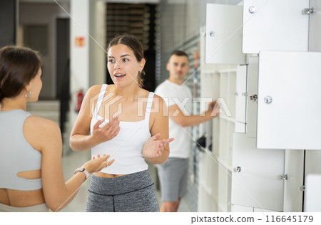 Girl enjoying chat with female friend by lockers at climbing gym Girl enjoying chat with female friend by lockers at climbing gym 116645179