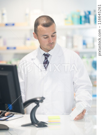 Young male pharmacist pushing medicine at cash register 116645261