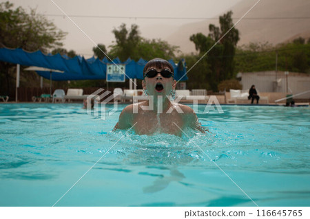 Boy with glasses swims in the pool Boy with glasses swims in the pool 116645765