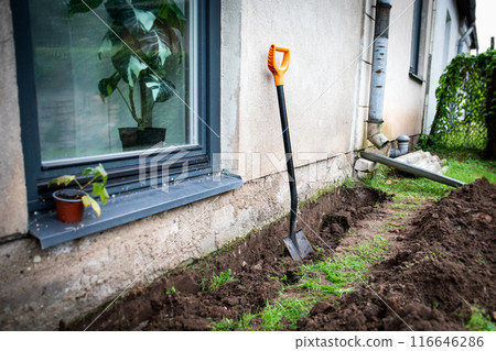 A trench at the foundation of the house and a shovel. Preparing for insulation and renovation of 116646286