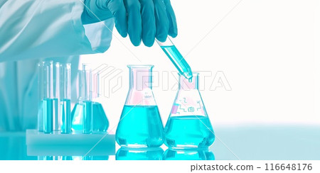 A gloved hand pouring liquid into a beaker in a laboratory setting. 116648176