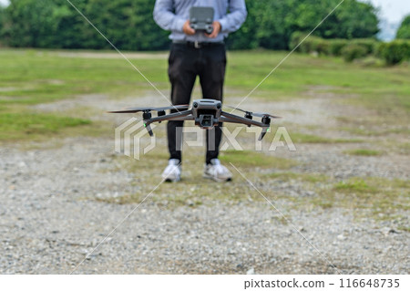 A hovering drone and a man piloting it A hovering drone and a man piloting it 116648735