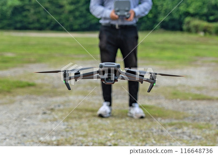 A hovering drone and a man piloting it A hovering drone and a man piloting it 116648736