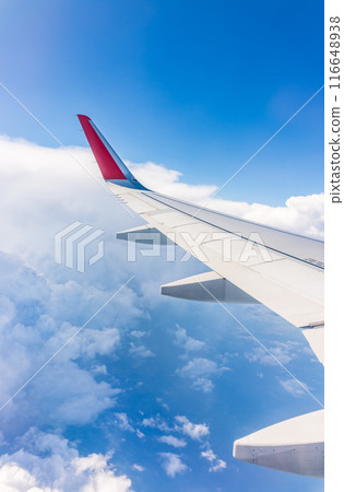 View from the airplane window at a beautiful cloudy sky and the airplane wing View from the airplane window at a beautiful cloudy sky and the airplane wing 116648938