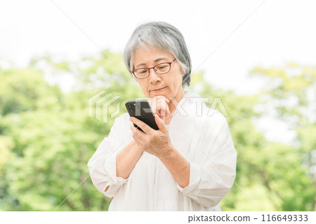 Elderly woman using a smartphone in the park (app, operation, search, photo, camera) Elderly woman using a smartphone in the park (app, operation, search, photo, camera) 116649333