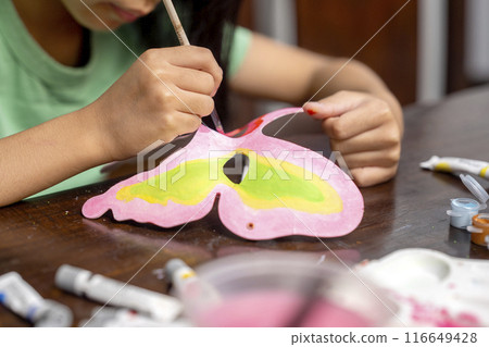 A little girl painting with a paintbrush and watercolor 116649428