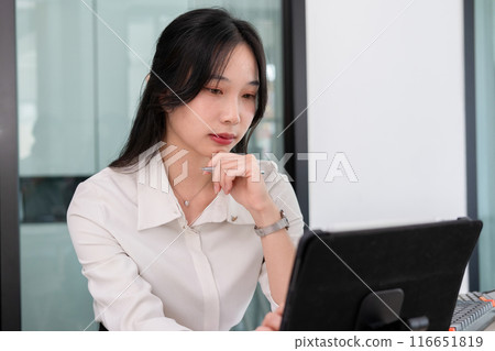 Young woman examines stock graphs at tablet 116651819