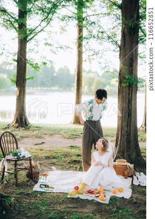Bride and groom having pre-wedding photos while having a picnic Bride and groom having pre-wedding photos while having a picnic 116652851