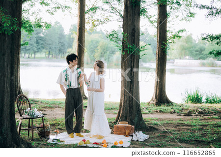 Bride and groom having pre-wedding photos while having a picnic Bride and groom having pre-wedding photos while having a picnic 116652865