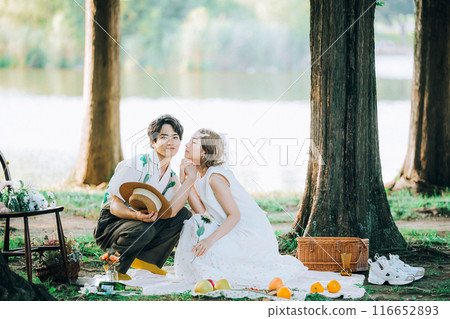 Bride and groom having pre-wedding photos while having a picnic Bride and groom having pre-wedding photos while having a picnic 116652893