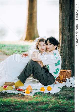 Bride and groom having pre-wedding photos while having a picnic Bride and groom having pre-wedding photos while having a picnic 116652906