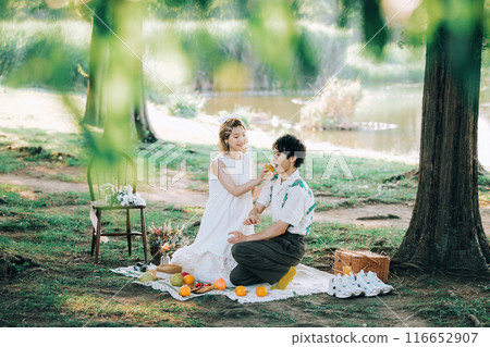Bride and groom having pre-wedding photos while having a picnic Bride and groom having pre-wedding photos while having a picnic 116652907