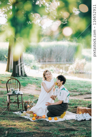 Bride and groom having pre-wedding photos while having a picnic 116652911