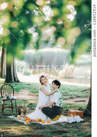 Bride and groom having pre-wedding photos while having a picnic Bride and groom having pre-wedding photos while having a picnic 116652914