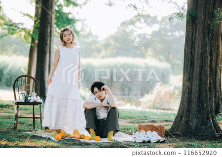 Bride and groom having pre-wedding photos while having a picnic 116652920
