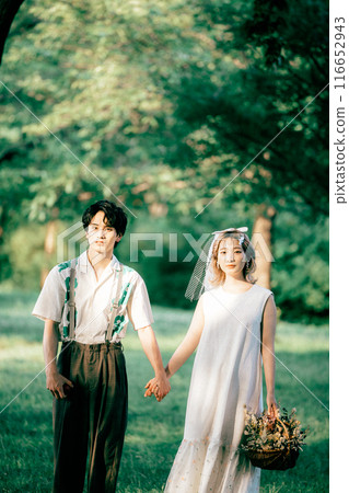 Bride and groom having pre-wedding photos while having a picnic 116652943