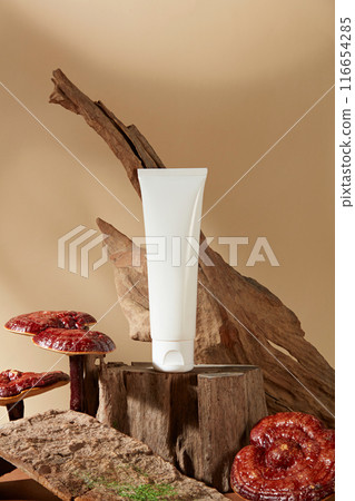 Unbranded tube in white color standing on a piece of tree with lingzhi mushrooms decorated around. Empty label for cosmetic product mockup. Lingzhi mushroom can boost your immune system 116654285