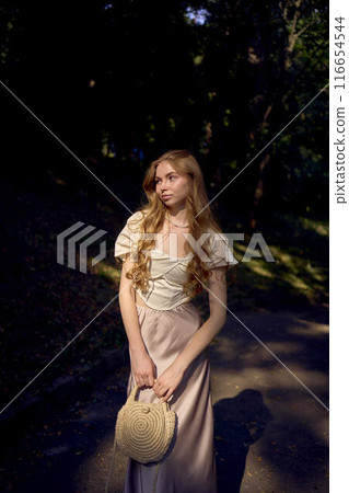 beautiful teenage girl in a silk skirt and a corset in the old money style walks in the park and along the river bank beautiful teenage girl in a silk skirt and a corset in the old money style walks in the park and along the river bank 116654544