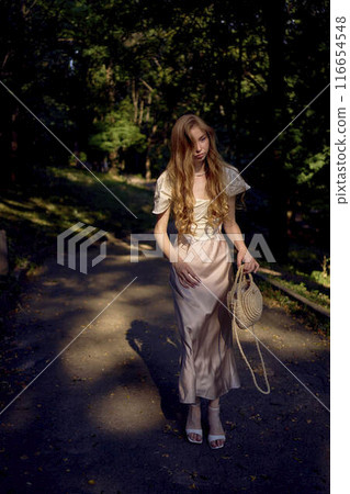 beautiful teenage girl in a silk skirt and a corset in the old money style walks in the park and along the river bank beautiful teenage girl in a silk skirt and a corset in the old money style walks in the park and along the river bank 116654548