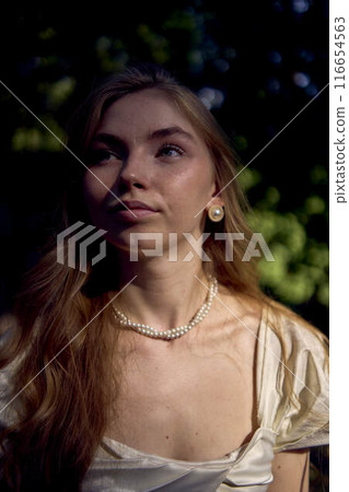 beautiful teenage girl in a silk skirt and a corset in the old money style walks in the park and along the river bank beautiful teenage girl in a silk skirt and a corset in the old money style walks in the park and along the river bank 116654563