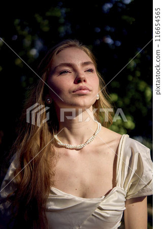 beautiful teenage girl in a silk skirt and a corset in the old money style walks in the park and along the river bank beautiful teenage girl in a silk skirt and a corset in the old money style walks in the park and along the river bank 116654565