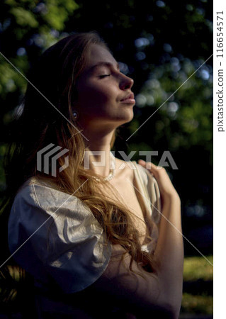 beautiful teenage girl in a silk skirt and a corset in the old money style walks in the park and along the river bank beautiful teenage girl in a silk skirt and a corset in the old money style walks in the park and along the river bank 116654571