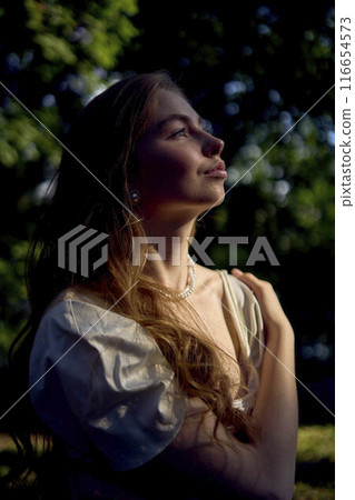 beautiful teenage girl in a silk skirt and a corset in the old money style walks in the park and along the river bank beautiful teenage girl in a silk skirt and a corset in the old money style walks in the park and along the river bank 116654573