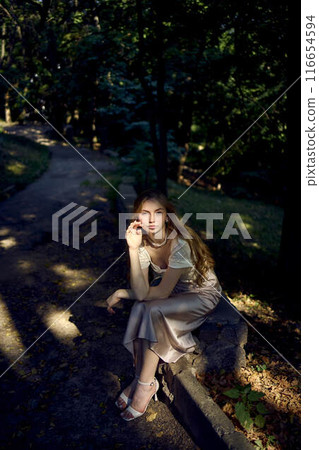 beautiful teenage girl in a silk skirt and a corset in the old money style walks in the park and along the river bank beautiful teenage girl in a silk skirt and a corset in the old money style walks in the park and along the river bank 116654594
