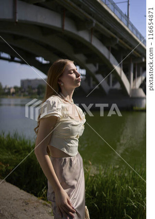 beautiful teenage girl in a silk skirt and corset in the old money style.  Fashion photoshoot under the bridge. 116654871