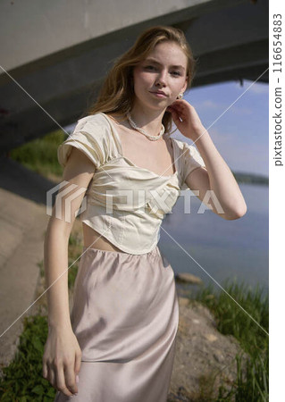 beautiful teenage girl in a silk skirt and corset in the old money style.  Fashion photoshoot under the bridge. 116654883