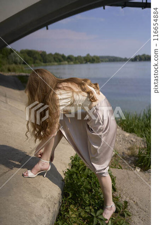 beautiful teenage girl in a silk skirt and corset in the old money style. Fashion photoshoot under the bridge. beautiful teenage girl in a silk skirt and corset in the old money style. Fashion photoshoot under the bridge. 116654884
