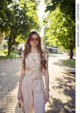 a beautiful teenage girl in a peach fuzz suit with a waistcoat, in the old money style walks through the morning city a beautiful teenage girl in a peach fuzz suit with a waistcoat, in the old money style walks through the morning city 116654890