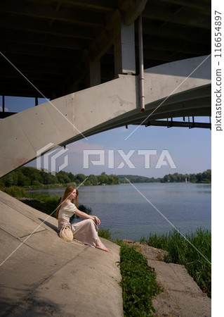 beautiful teenage girl in a silk skirt and corset in the old money style.  Fashion photoshoot under the bridge. 116654897