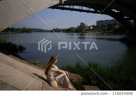 beautiful teenage girl in a silk skirt and corset in the old money style.  Fashion photoshoot under the bridge. 116654906