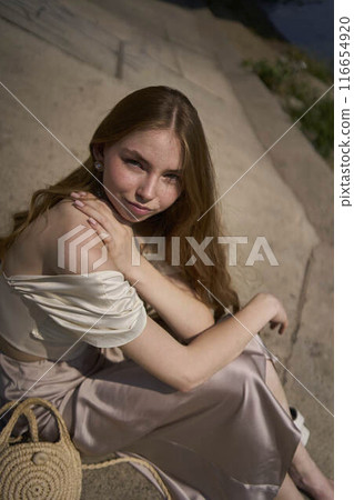 beautiful teenage girl in a silk skirt and corset in the old money style.  Fashion photoshoot under the bridge. 116654920