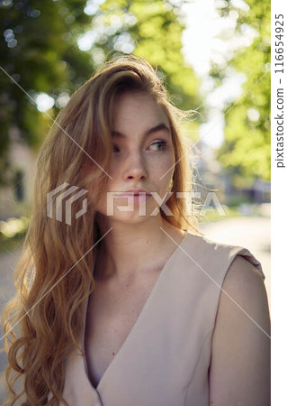 a beautiful teenage girl in a peach fuzz suit with a waistcoat, in the style of old money walks through the morning city 116654925