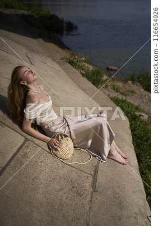 beautiful teenage girl in a silk skirt and corset in the old money style.  Fashion photoshoot under the bridge. 116654926