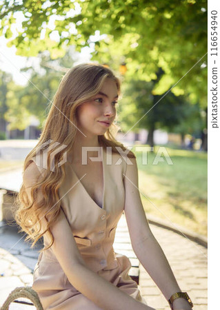a beautiful teenage girl in a peach fuzz suit with a waistcoat, in the old money style  walks through the morning city 116654940