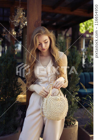 a  beautiful teenage girl in a peach fuzz suit with a vest, in the old money style in a fancy restaurant 116654950
